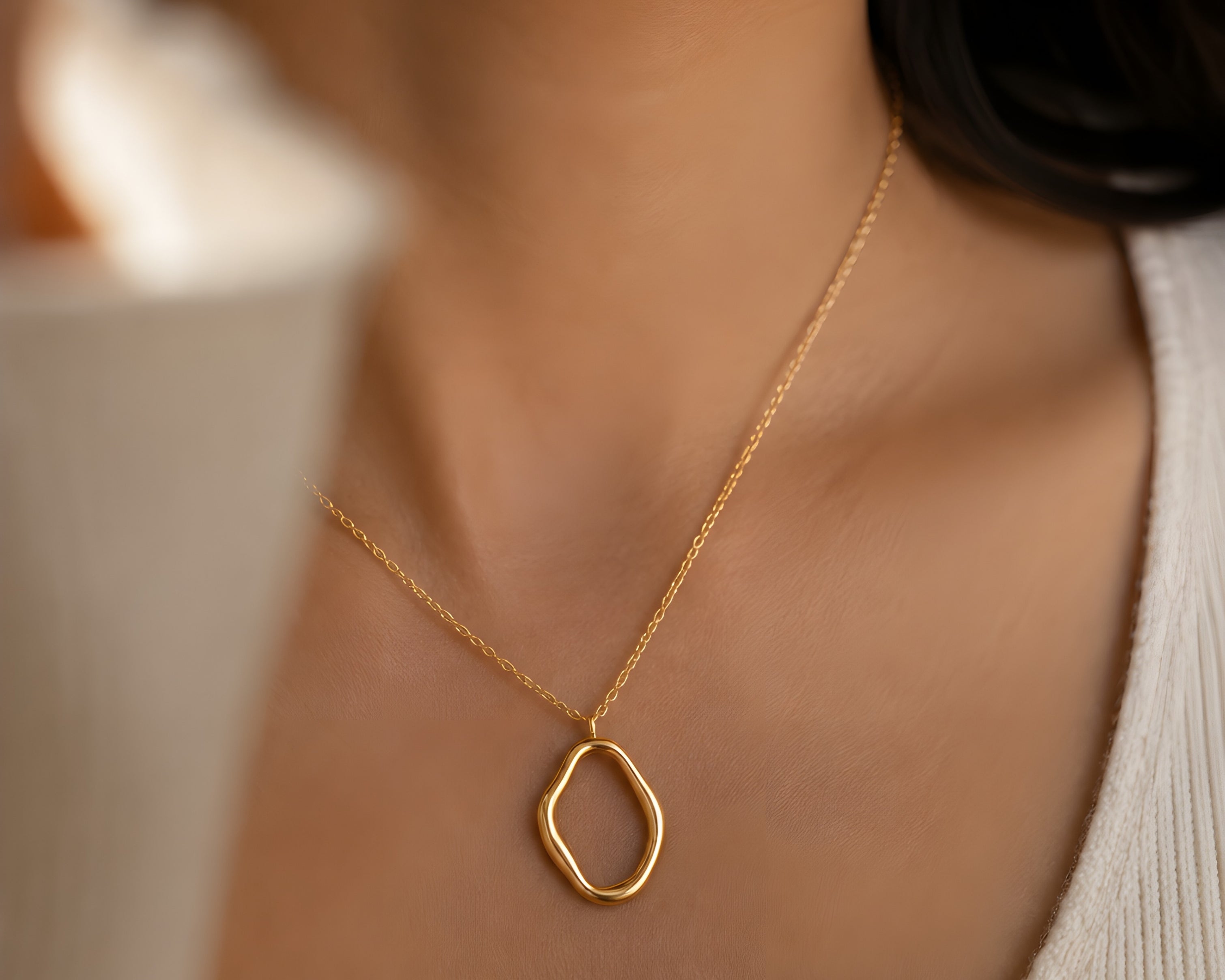 Salve abstract gold-toned pendant necklace with modern design, featuring a sleek, artistic pendant on a chain.