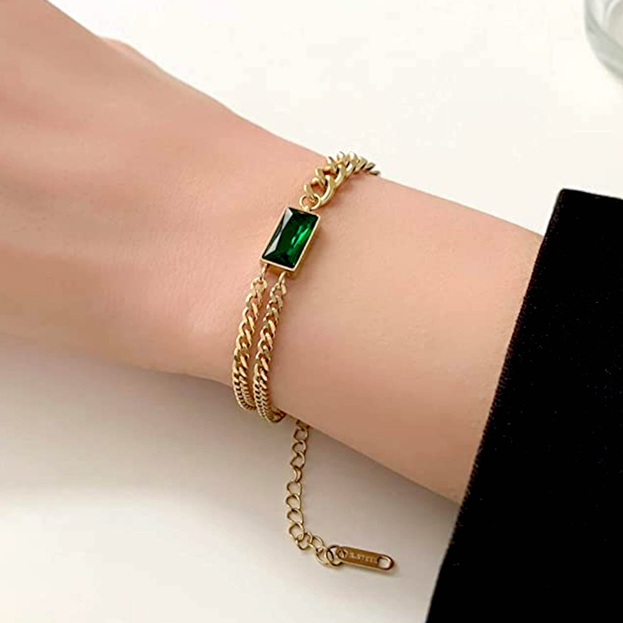 Band style bracelet in gold plating with gold plated details and emerald  green colour stones 