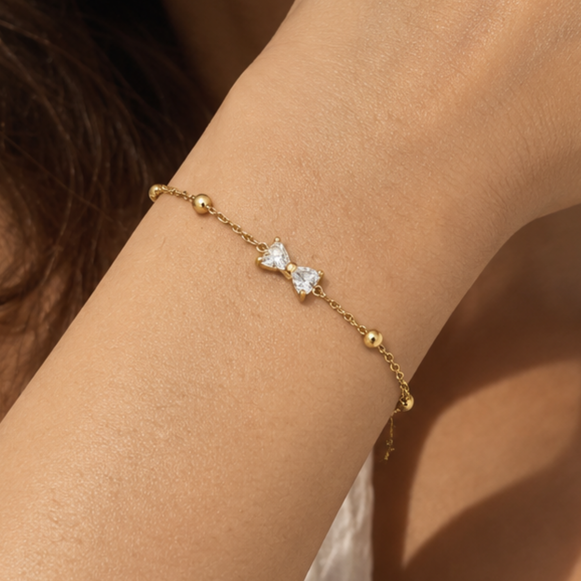 Gold-toned SALVE bow bracelet with delicate design, featuring a stylish bow charm on a sleek bracelet band.