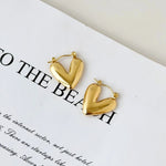 SALVE hinged hoop heart earrings featuring gold-tone hoops with a hinged clasp and heart-shaped design, stylish and elegant jewelry.