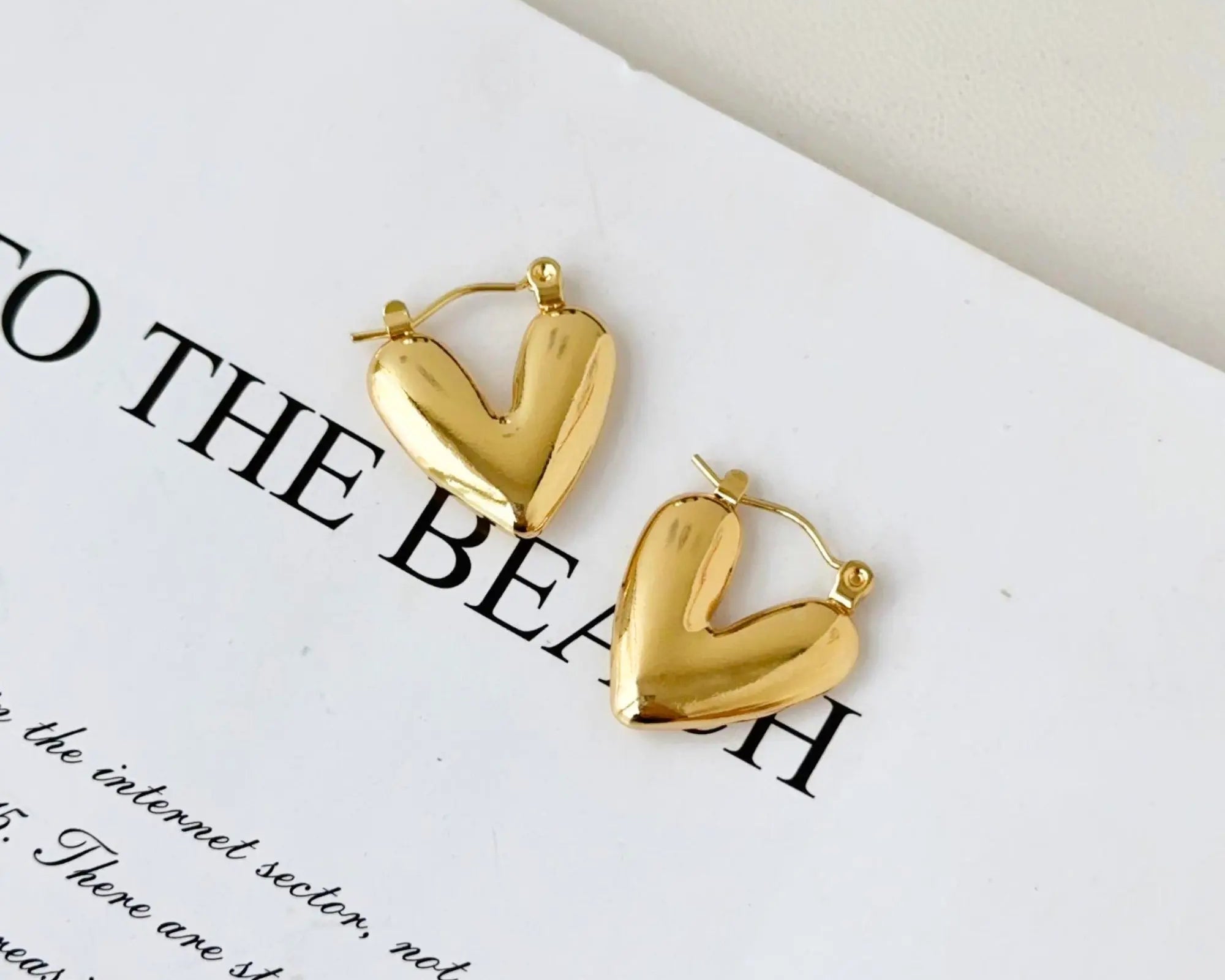 SALVE hinged hoop heart earrings featuring gold-tone hoops with a hinged clasp and heart-shaped design, stylish and elegant jewelry.