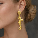 Gold sea horse drop dangle earrings by SALVE featuring intricate sea horse designs and elegant dangling style.