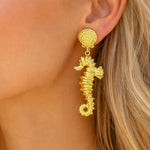 Gold sea horse drop dangle earrings by SALVE featuring intricate sea horse design and elegant dangling style.