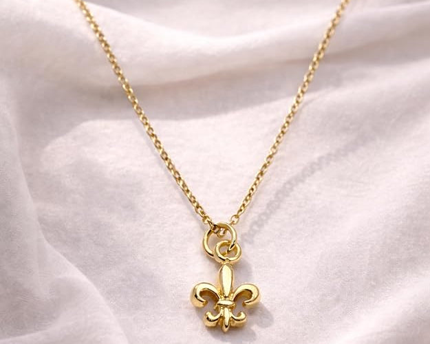 Salve Fleur de Lis pendant necklace featuring a detailed gold-tone pendant hanging from a delicate chain.