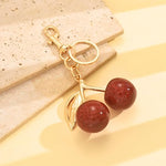 Red glitter cherry keychain by SALVE featuring a sparkling cherry charm with a metal keyring attachment.