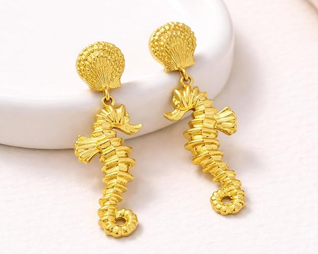 Gold sea horse drop dangle earrings by SALVE featuring intricate sea horse design hanging from delicate hooks