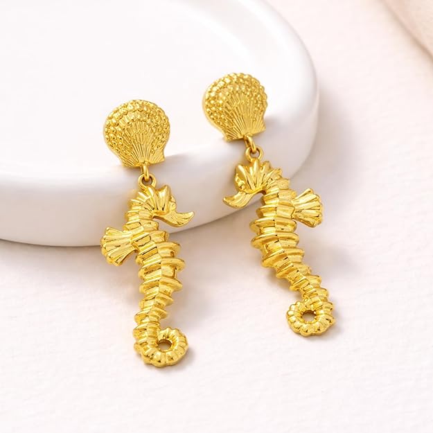 Gold sea horse drop dangle earrings by SALVE featuring intricate sea horse design hanging from delicate hooks