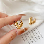 Salve hinged hoop heart earrings featuring gold-tone metal with a delicate heart-shaped design and secure clasp.
