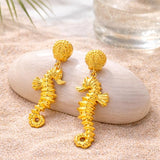 Gold sea horse drop dangle earrings by SALVE featuring detailed sea horse design and elegant dangling style.