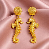 Gold drop earrings featuring sea horse dangles from SALVE, showcasing intricate marine-inspired jewelry design.